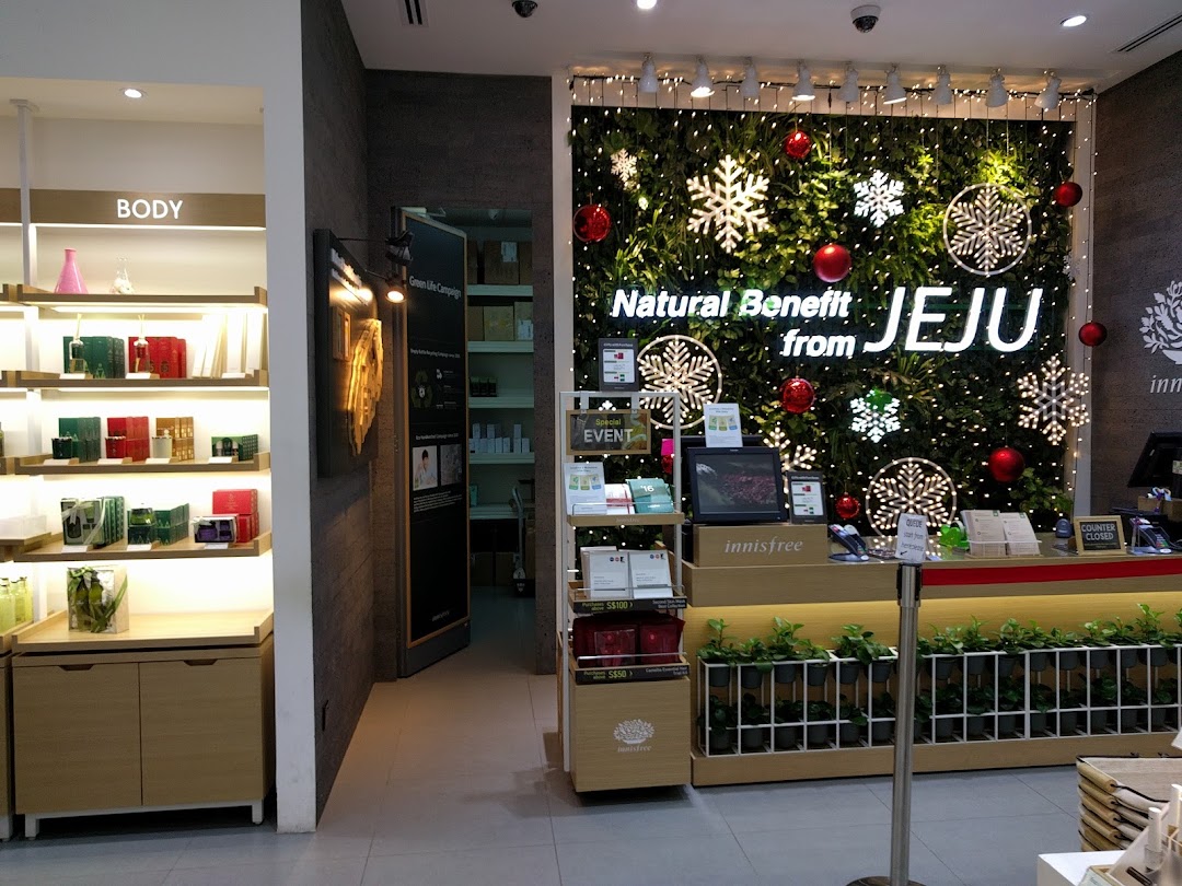 Interior view of Innisfree store featuring product displays, a counter, and a festive 'Natural Benefit from JEJU' wall.