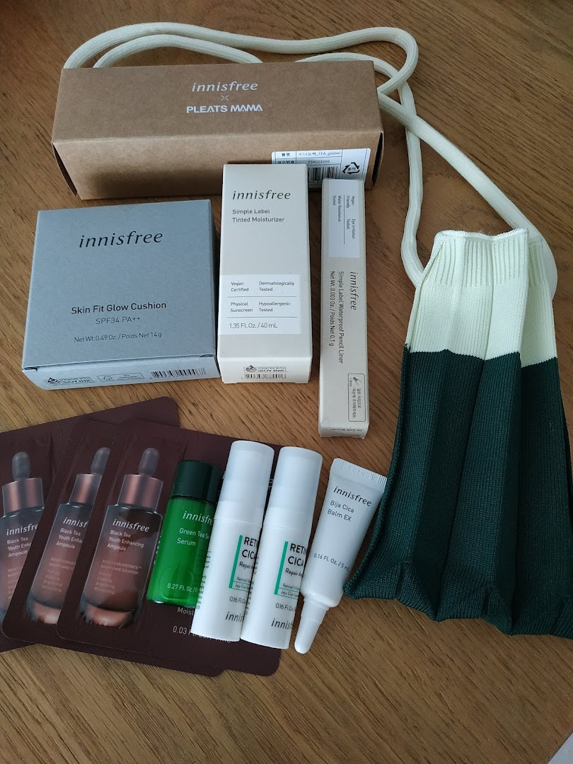 A collection of Innisfree skincare and makeup products, including cushions, moisturizers, and samples, displayed with a reusable bag.