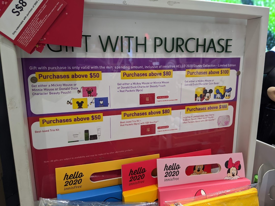 A display board showcasing Innisfree's 'Gift with Purchase' promotions featuring Disney characters and beauty kits.