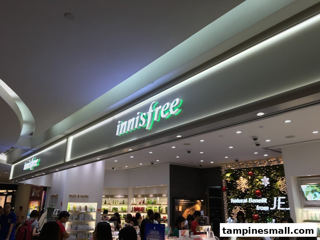 The Innisfree shop entrance with its illuminated green sign and customers browsing inside.