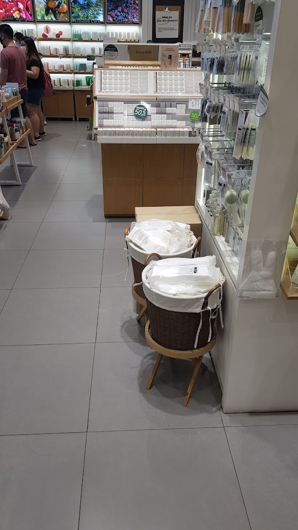 An interior view of Innisfree, showcasing skincare products, makeup tools, and customers browsing.