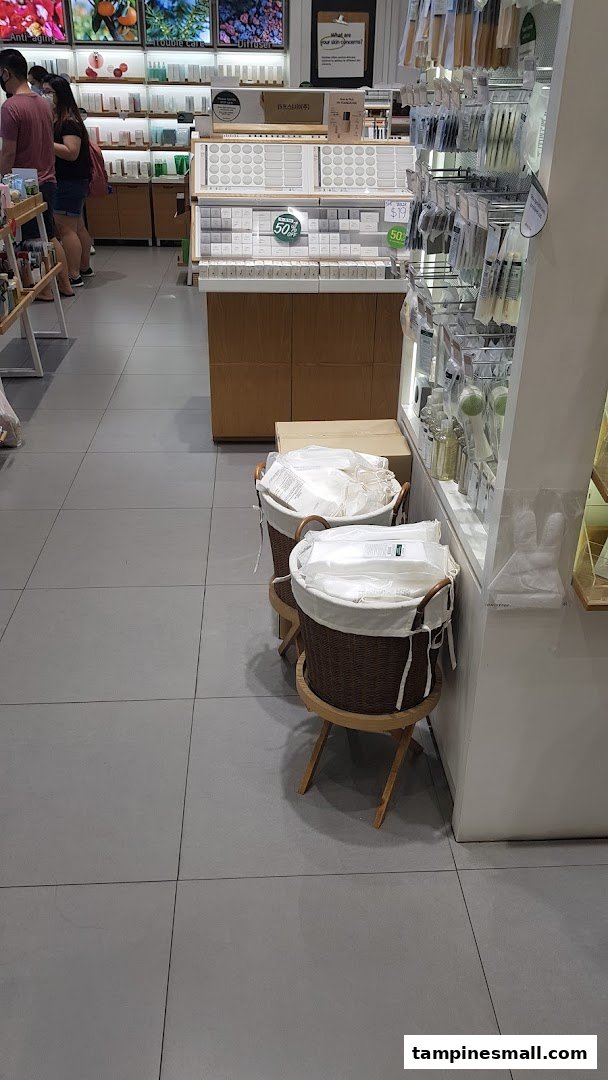 An interior view of Innisfree, showcasing skincare products, makeup tools, and customers browsing.