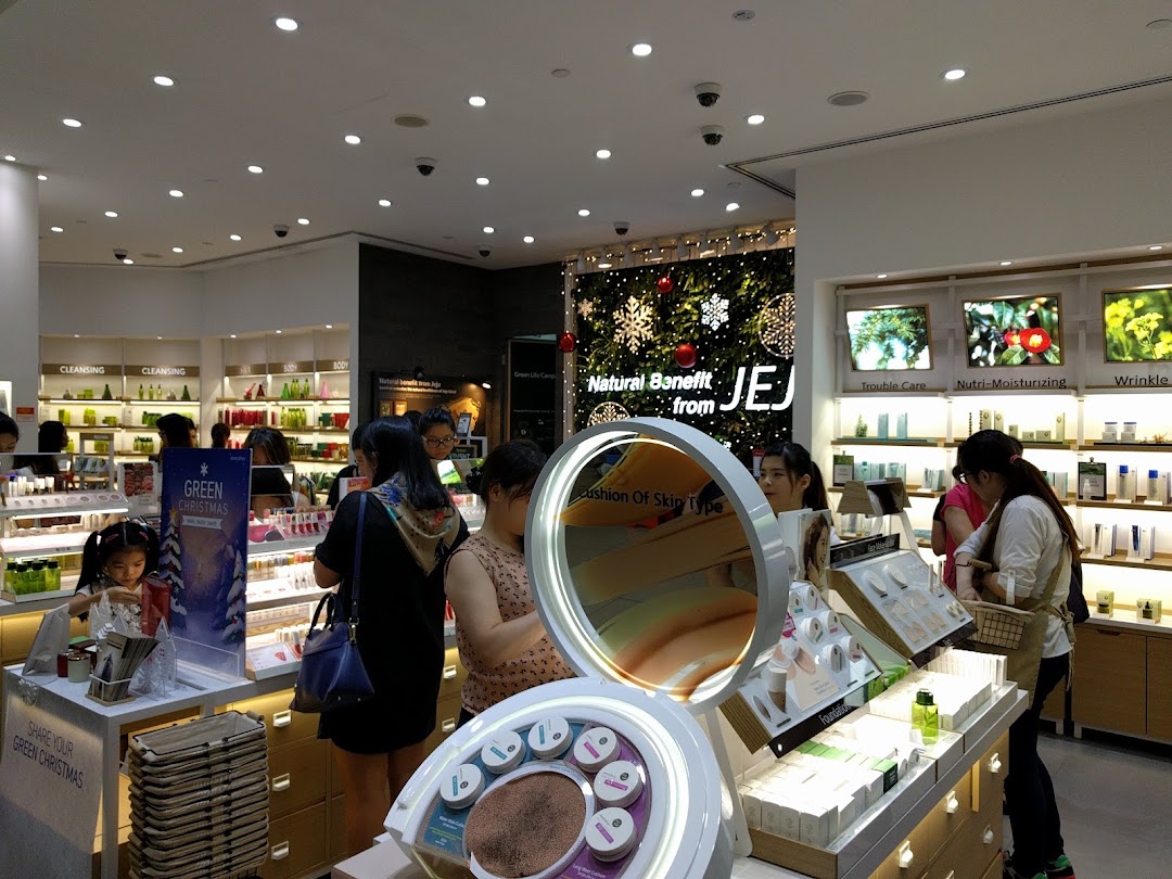 Customers browse natural skincare and makeup products in a brightly lit Innisfree store, featuring festive decorations.