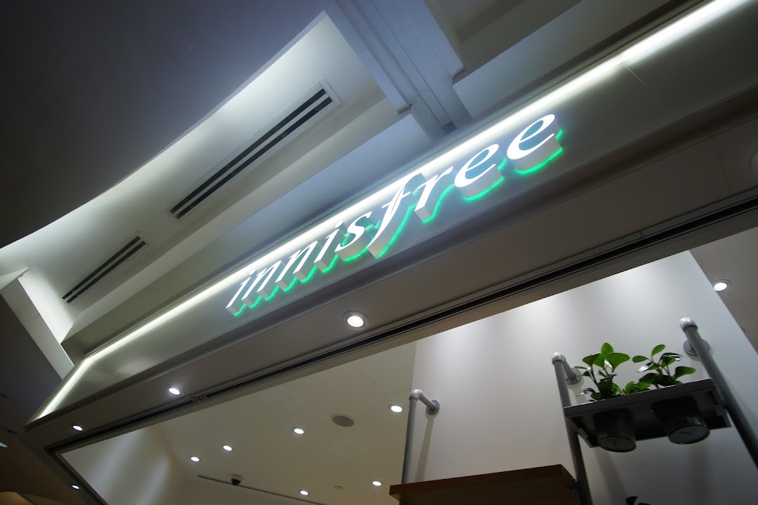 The illuminated Innisfree logo with green accents above the shop entrance.