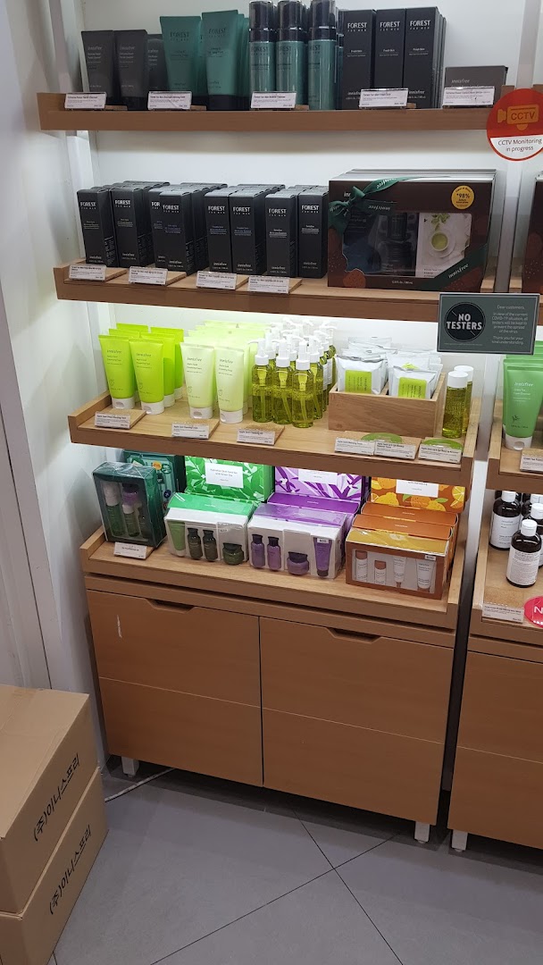 Innisfree skincare products, including Forest for Men and Apple Seed lines, displayed on wooden shelves.