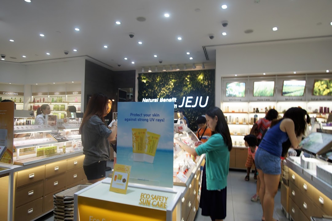 Customers browse skincare and beauty products inside a brightly lit Innisfree store featuring natural Jeju-inspired displays.