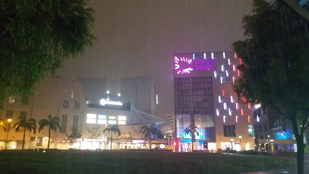 Night view of Century Square shopping mall exterior with illuminated signs and palm trees.