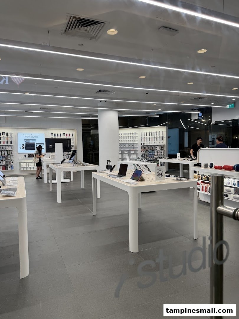 Interior view of iStudio, an electronics store, featuring display tables with devices and accessories.