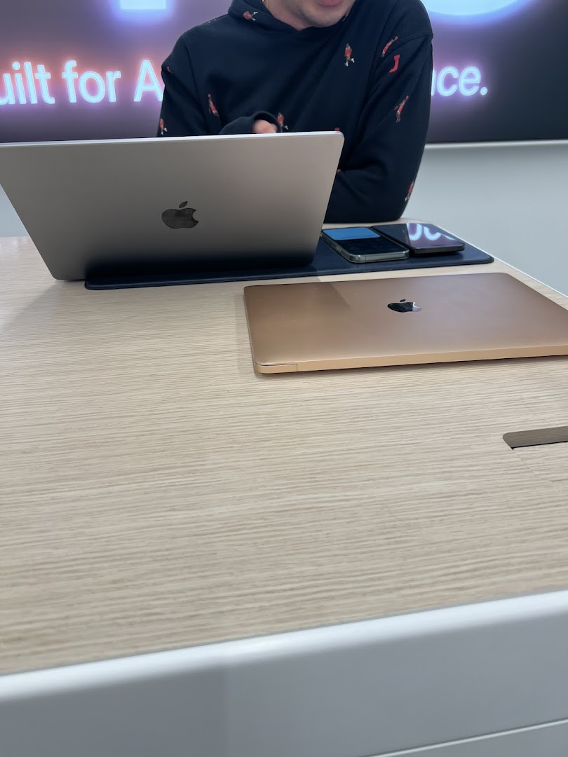 A customer interacts with Apple products on display at iStudio, showcasing MacBooks and iPhones.