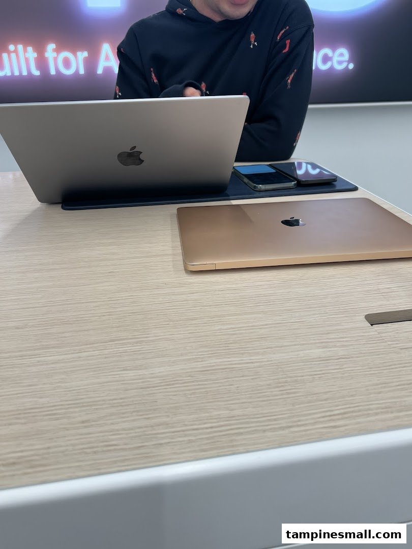 A customer interacts with Apple products on display at iStudio, showcasing MacBooks and iPhones.