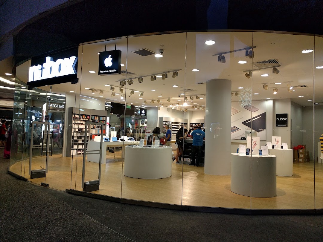 The brightly lit glass facade of an Apple Premium Reseller shop, 'nubox', showcasing its interior.