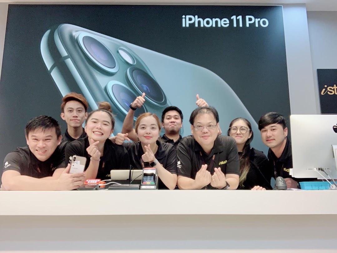 Smiling iStudio staff members pose behind a counter with an iPhone 11 Pro display in the background.