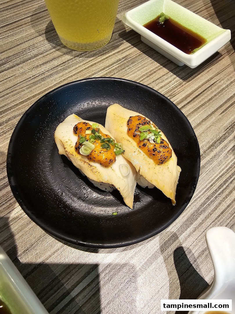 Two pieces of delicious sushi with savory toppings on a black plate, ready to be enjoyed at Itacho Sushi.