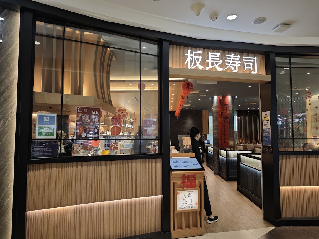 Exterior view of Itacho Sushi restaurant entrance with traditional Japanese decor and a staff member.