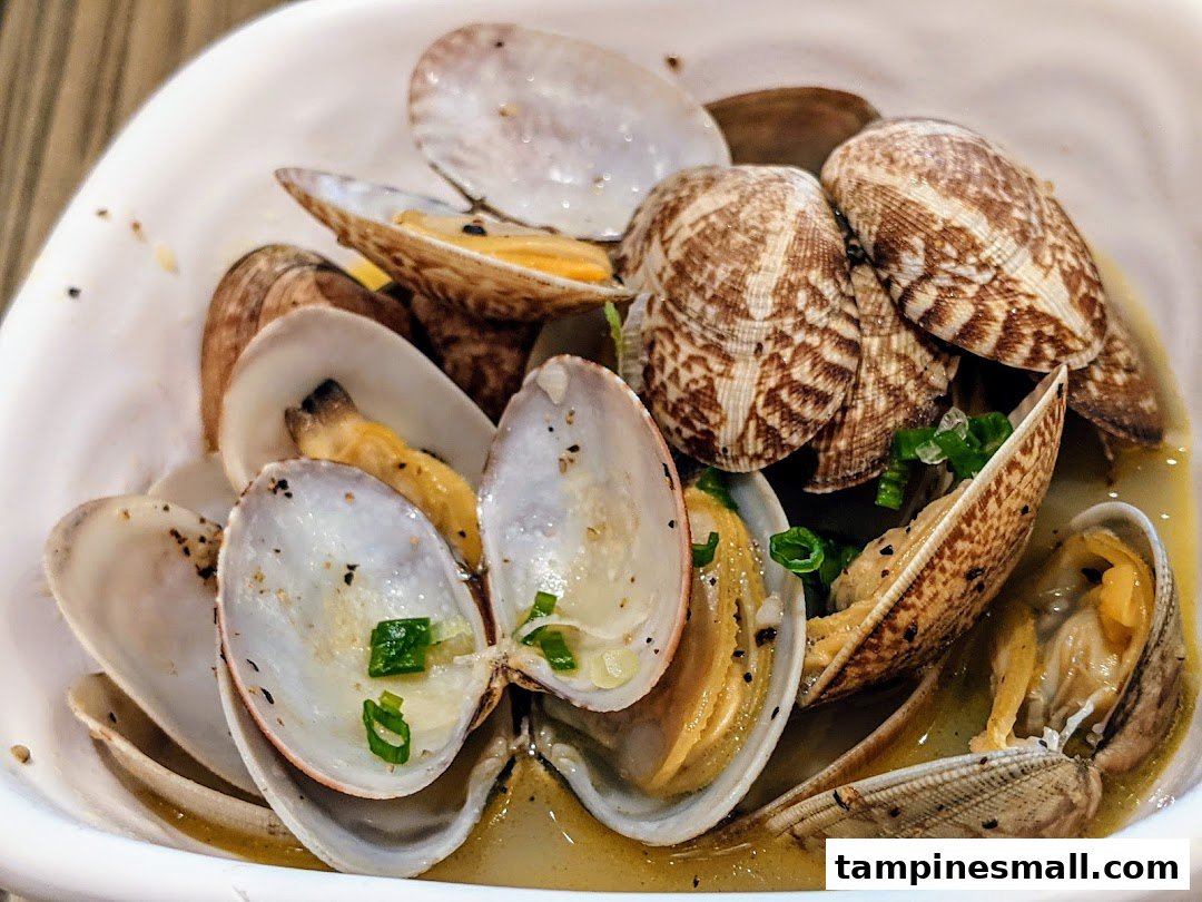 A close-up of a bowl of steamed clams garnished with green onions and black pepper.