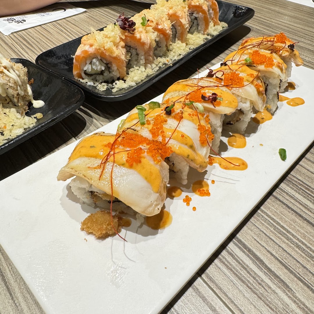 Delicious sushi rolls featuring seared scallops with roe and crispy salmon, served on elegant plates.