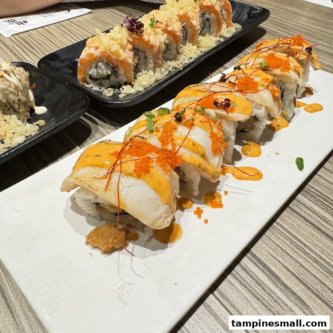 Delicious sushi rolls featuring seared scallops with roe and crispy salmon, served on elegant plates.