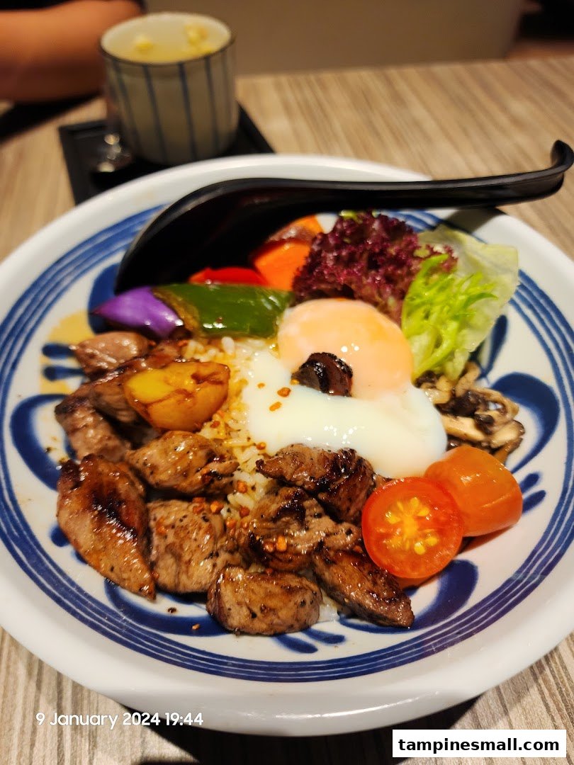 A close-up of a delicious beef donburi bowl with a poached egg, vegetables, and rice.