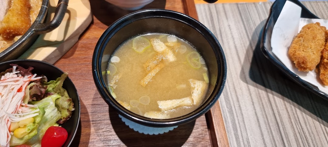 A close-up of a Japanese meal featuring miso soup, a fresh salad, and crispy fried items.