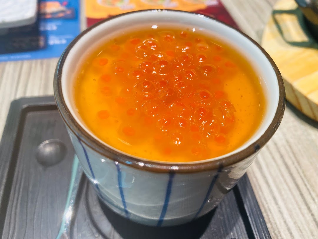 A close-up of a delicate chawanmushi (steamed egg custard) topped with vibrant orange salmon roe (ikura).