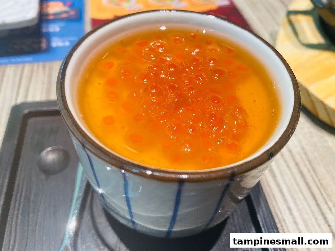 A close-up of a delicate chawanmushi (steamed egg custard) topped with vibrant orange salmon roe (ikura).