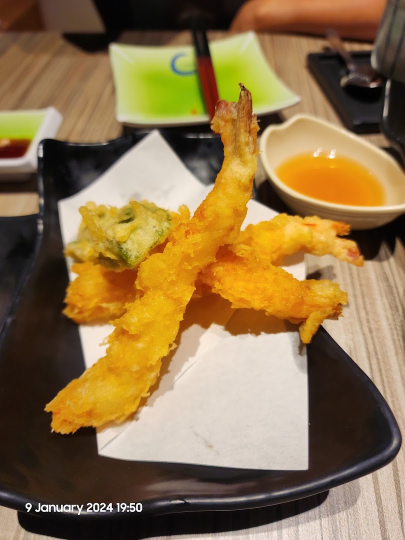 Crispy golden tempura shrimp and vegetables served on a black plate with dipping sauce.