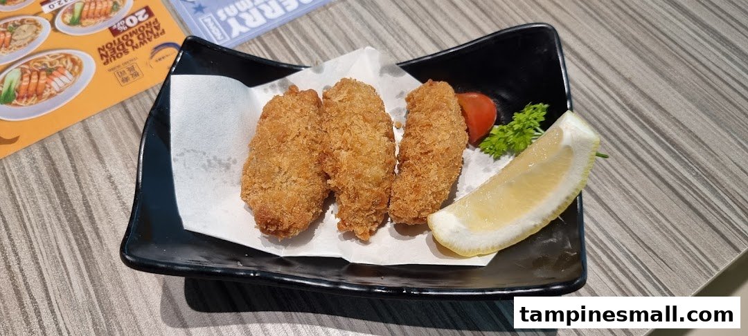 A plate of golden-fried items, possibly oysters or cutlets, served with a lemon wedge and garnish.