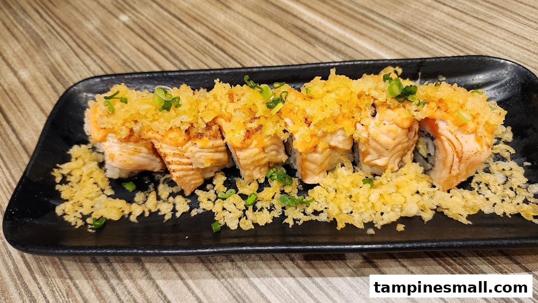 A close-up of a delicious salmon sushi roll topped with crispy tempura flakes and green onions.