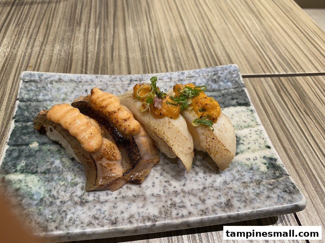 A plate of delicious sushi featuring torched salmon and white fish with uni topping.