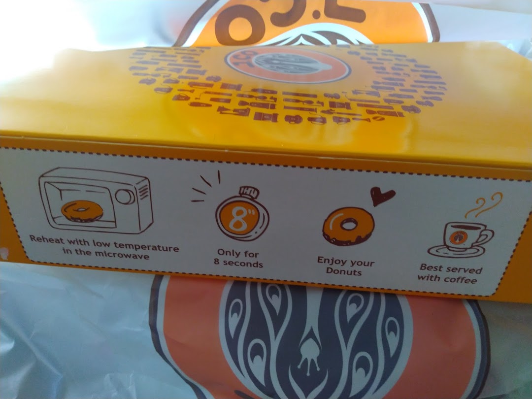 Close-up of a J.Co Donuts box displaying reheating instructions and serving suggestions.