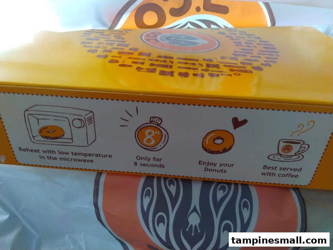 Close-up of a J.Co Donuts box displaying reheating instructions and serving suggestions.