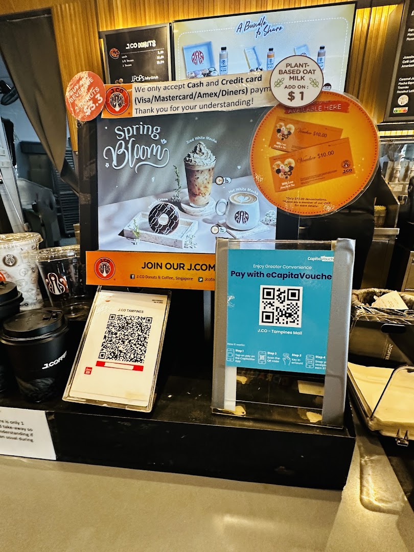 A counter display at J.Co Donuts & Coffee featuring promotional offers, payment options, and seasonal drinks.