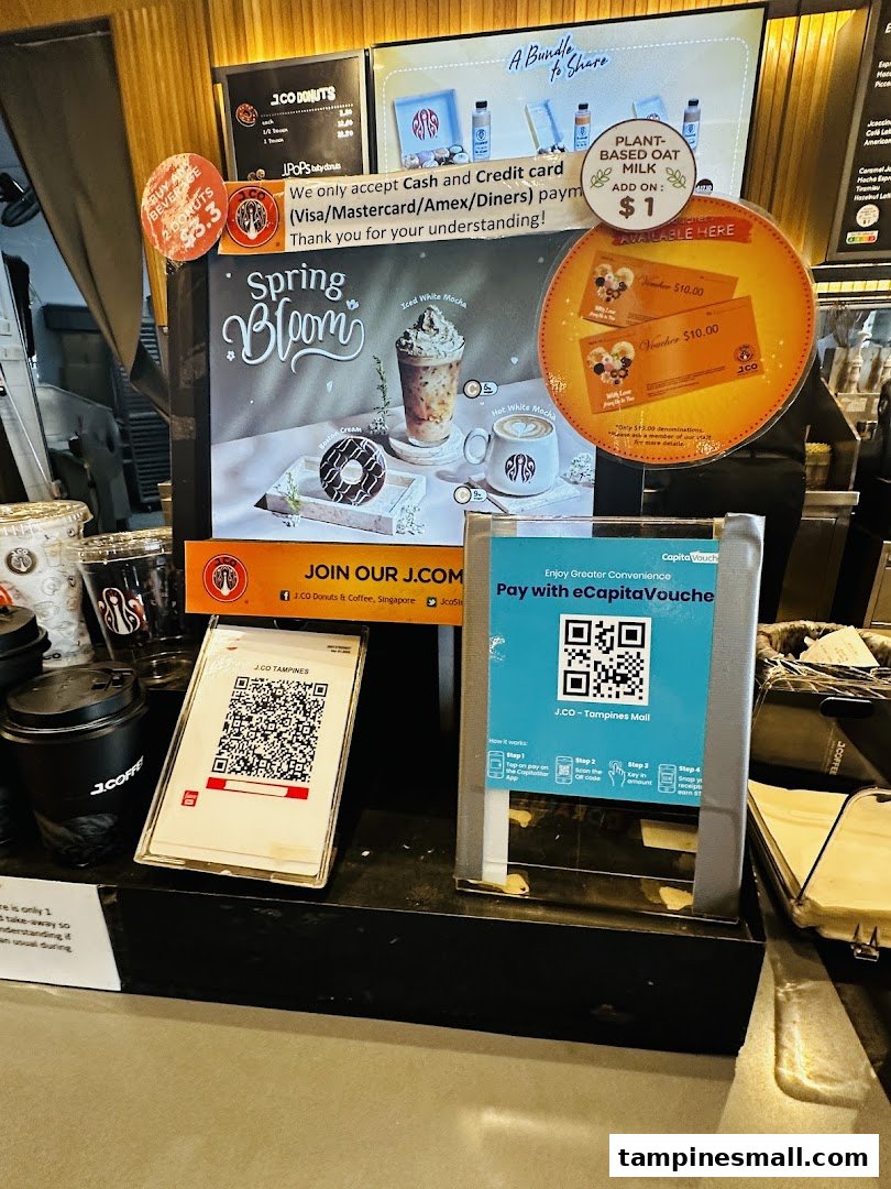 A counter display at J.Co Donuts & Coffee featuring promotional offers, payment options, and seasonal drinks.