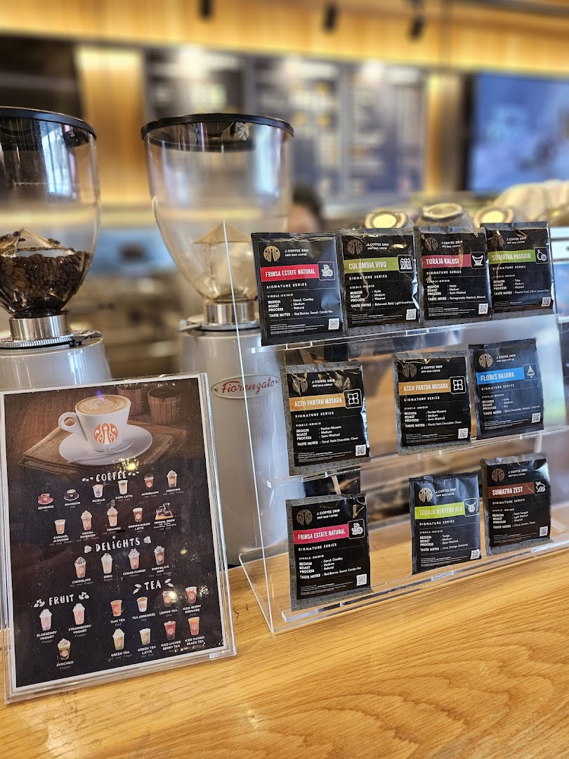 A counter display at J.Co Donuts & Coffee featuring coffee beans, grinders, and a detailed beverage menu.