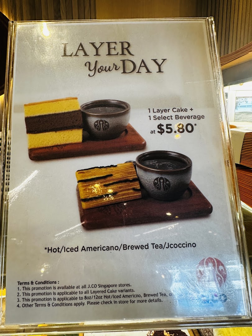 A promotional menu board displaying a 'Layer Your Day' offer with layered cake and beverage.