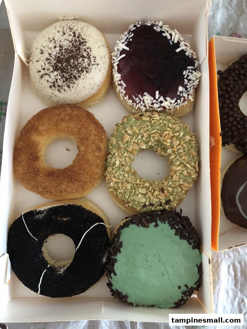 A box of assorted J.Co Donuts featuring various colorful glazes and toppings.