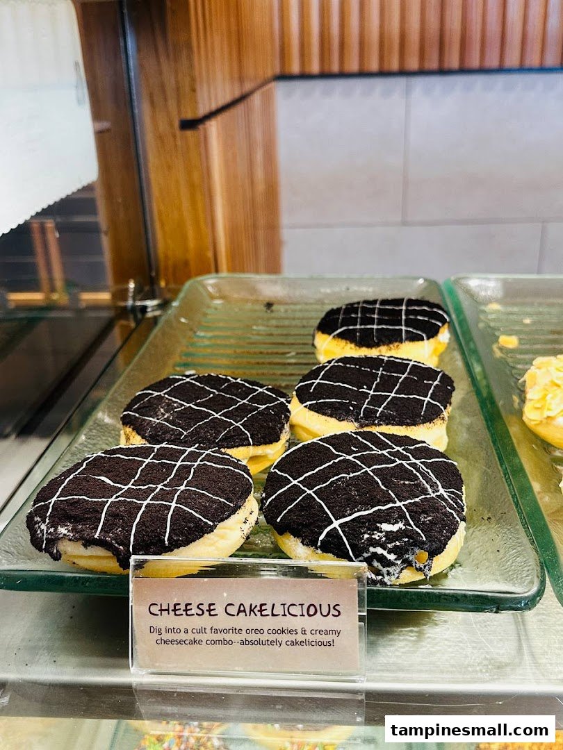 Close-up of J.Co's 'Cheese Cakelicious' donuts displayed in a glass case.