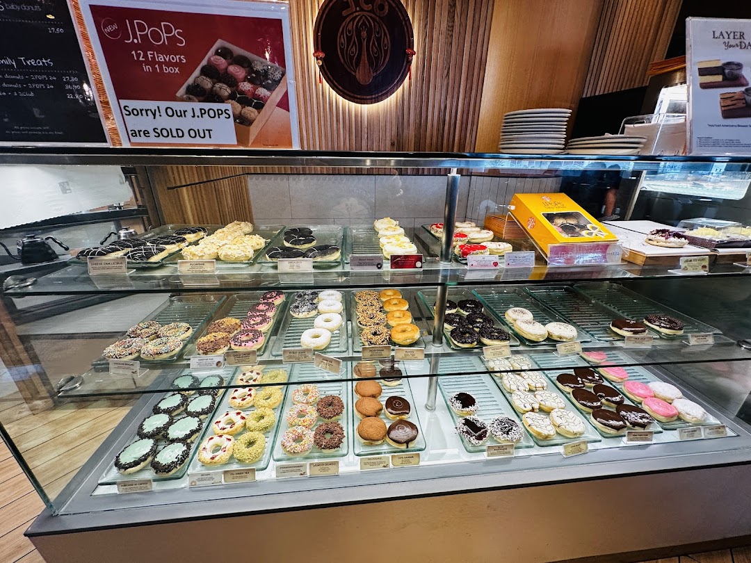 A vibrant display case showcasing a wide variety of colorful donuts and pastries at J.Co Donuts.