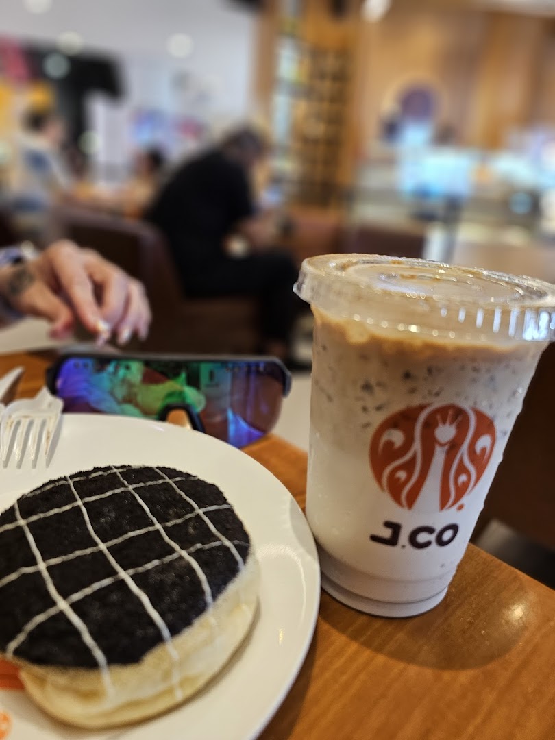 A delicious J.Co donut and iced coffee on a table inside the cafe.
