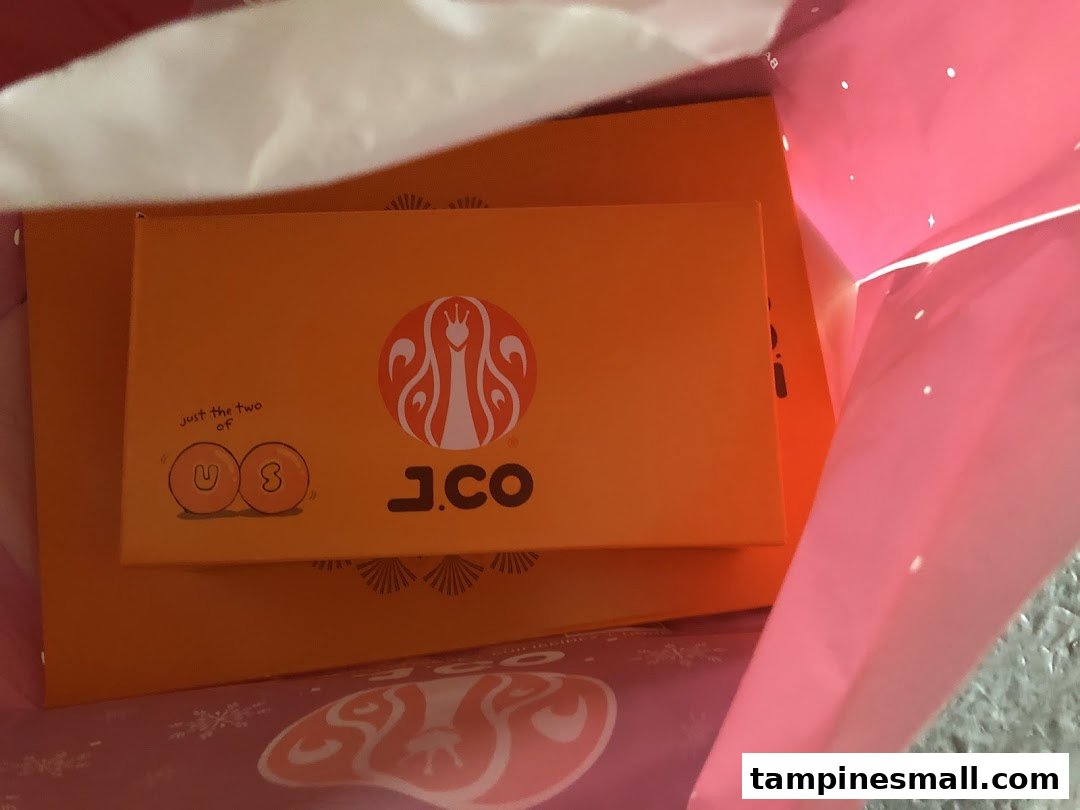 J.Co Donuts & Coffee boxes with branding inside a pink shopping bag.