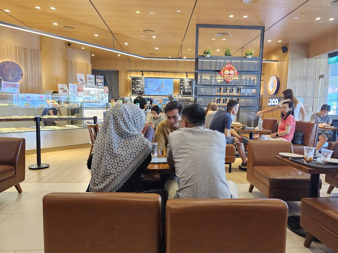 Customers enjoying fresh donuts and coffee in the modern, inviting interior of J.Co Donuts & Coffee.