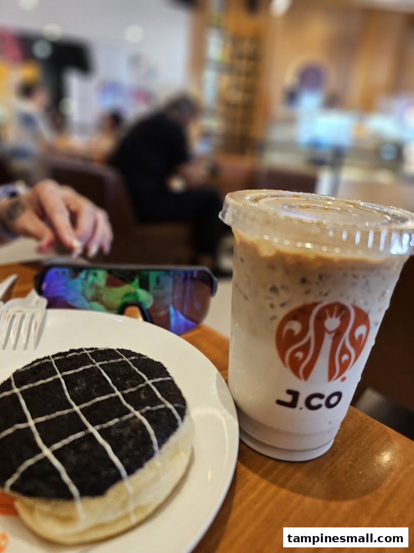 A delicious J.Co donut and iced coffee on a table inside the cafe.