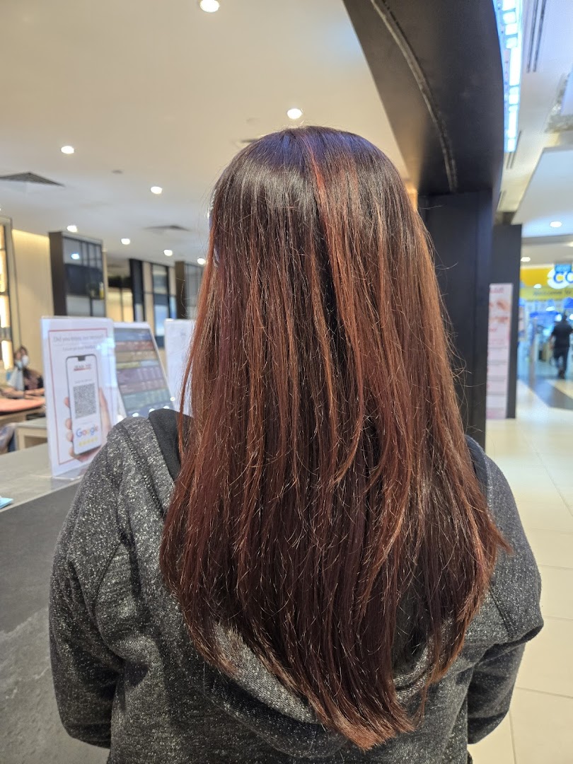 View of a person's long, reddish-brown hair from behind, inside a salon or mall.
