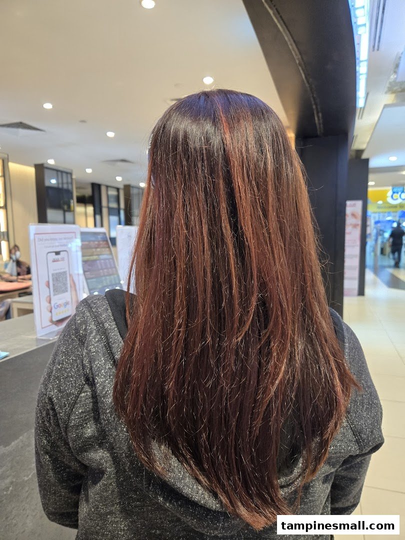 View of a person's long, reddish-brown hair from behind, inside a salon or mall.