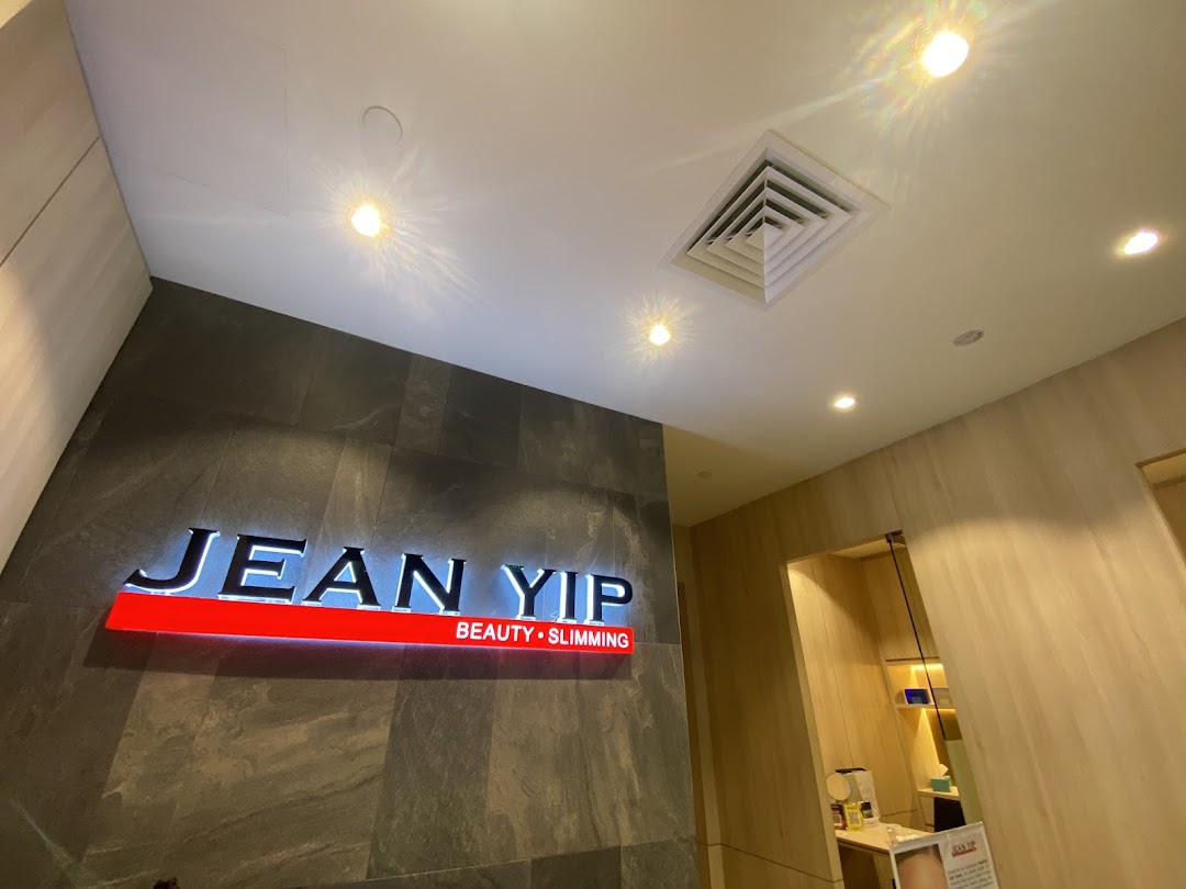 Illuminated 'Jean Yip Beauty • Slimming' sign on a dark textured wall.