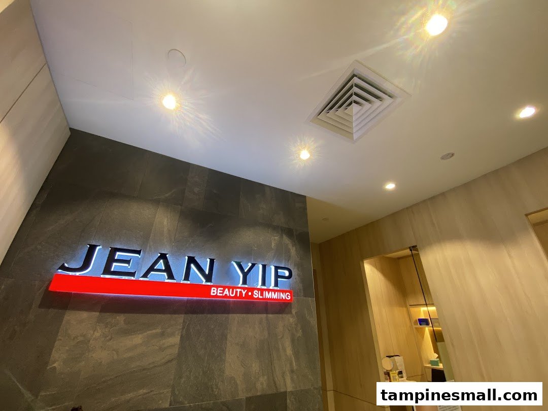 Illuminated 'Jean Yip Beauty • Slimming' sign on a dark textured wall.