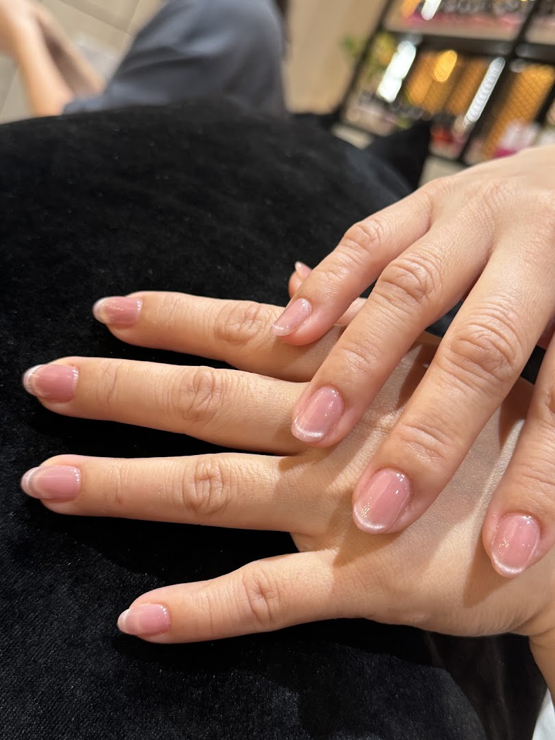 Close-up of hands with freshly manicured nails, showcasing a natural pink polish.