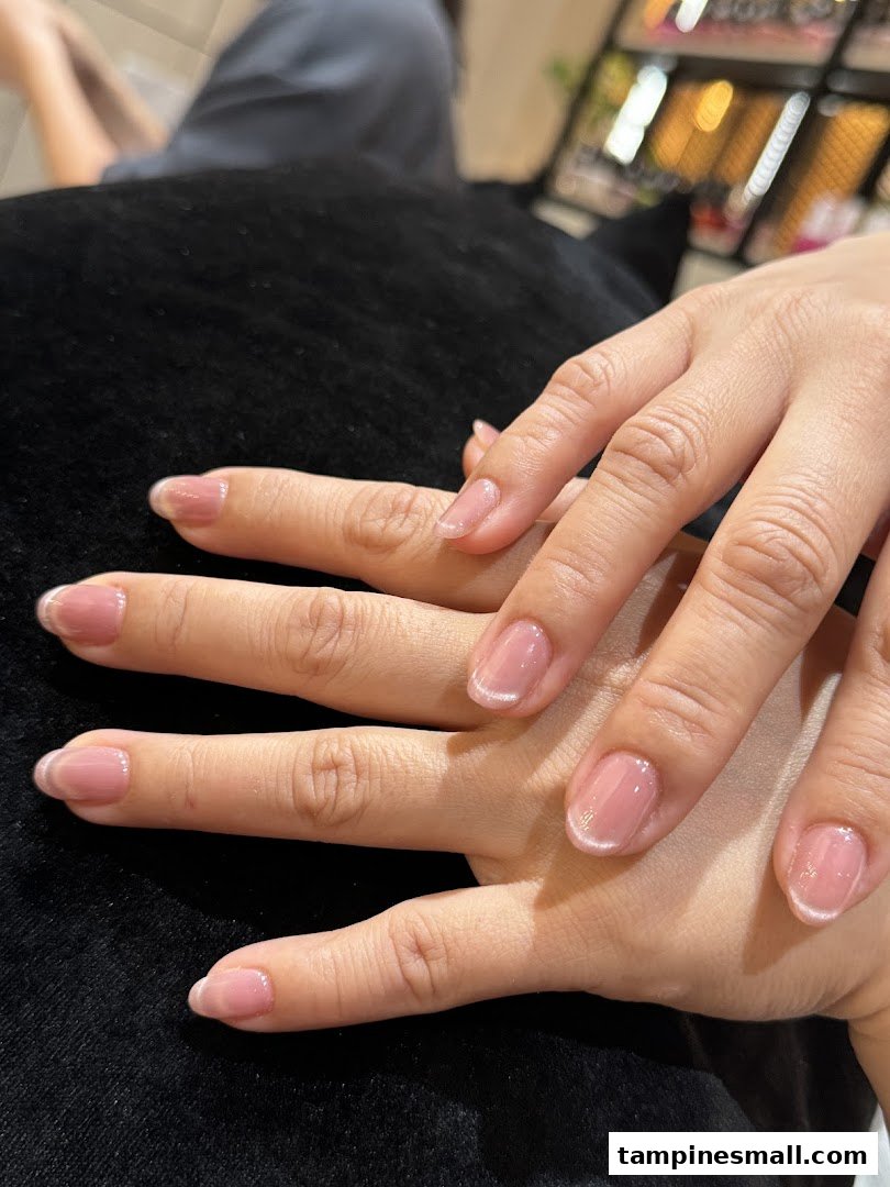 Close-up of hands with freshly manicured nails, showcasing a natural pink polish.