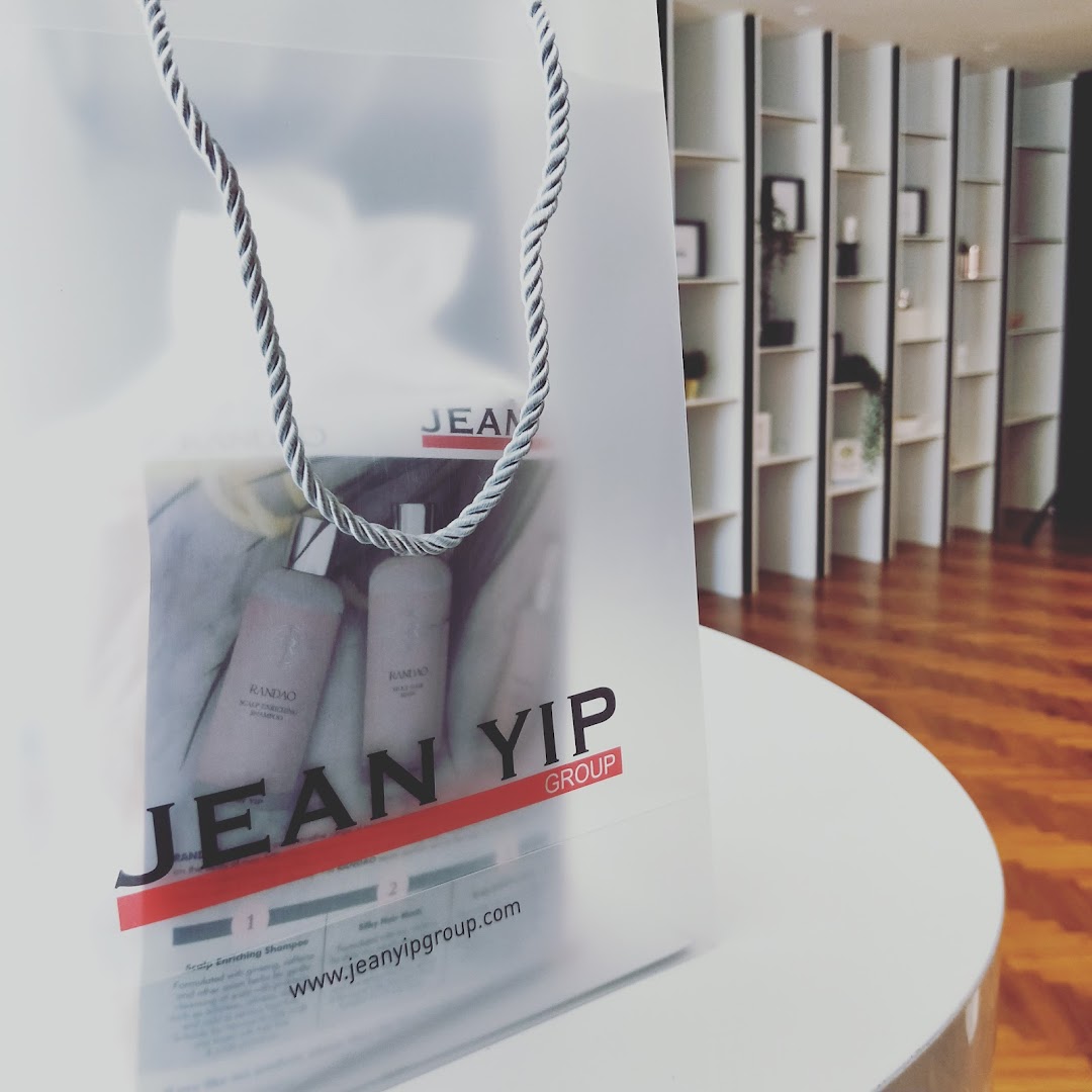 A translucent Jean Yip shopping bag with hair products inside, set against a modern salon interior.