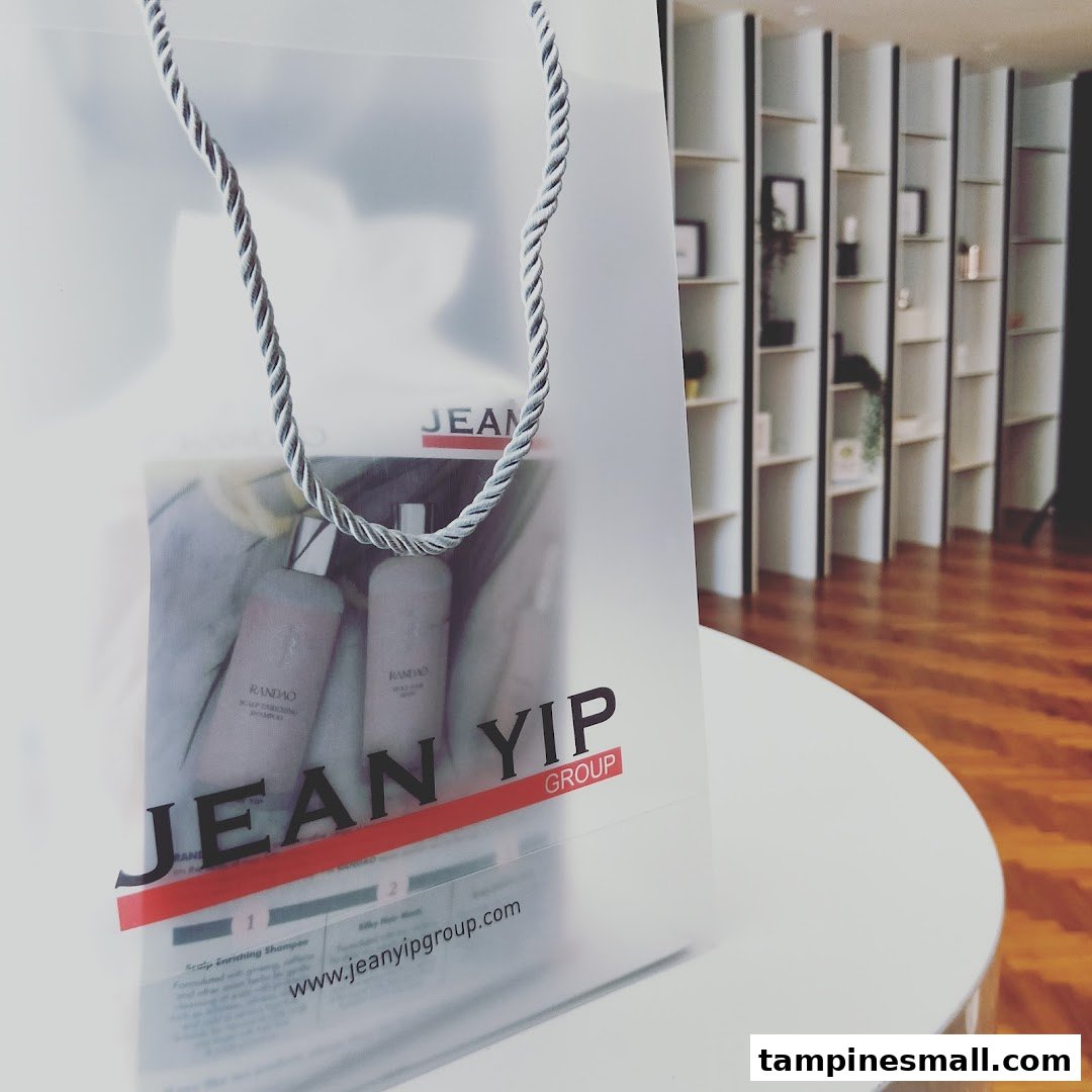 A translucent Jean Yip shopping bag with hair products inside, set against a modern salon interior.
